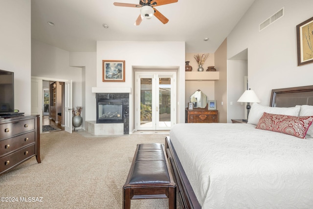 bedroom featuring lofted ceiling, light carpet, access to outside, a tile fireplace, and ceiling fan