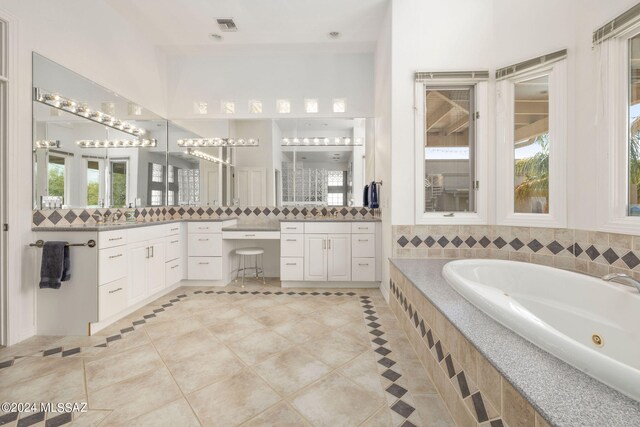 bathroom featuring tile floors, tiled tub, and vanity