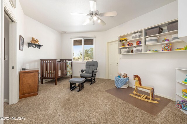 bedroom featuring carpet flooring, a crib, and ceiling fan