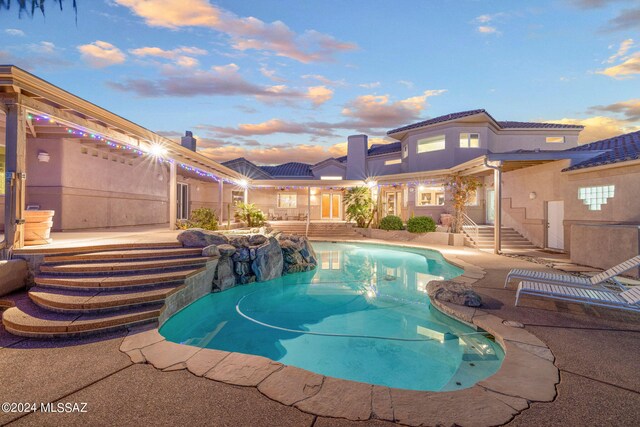 pool at dusk featuring a patio area