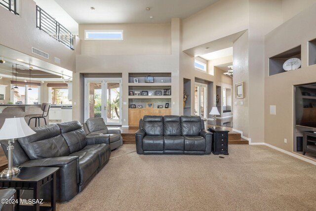 living room with a towering ceiling, built in features, and hardwood / wood-style floors