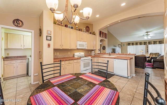 kitchen featuring kitchen peninsula, white appliances, ceiling fan with notable chandelier, sink, and decorative light fixtures