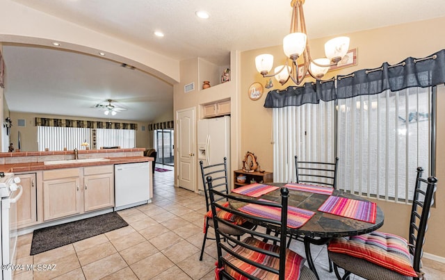 kitchen with ceiling fan with notable chandelier, white appliances, sink, light tile patterned floors, and hanging light fixtures