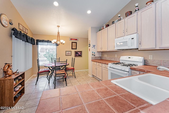 kitchen with white cabinetry, sink, hanging light fixtures, an inviting chandelier, and white appliances