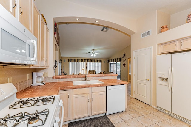 kitchen featuring white appliances, sink, ceiling fan, light tile patterned floors, and tile counters