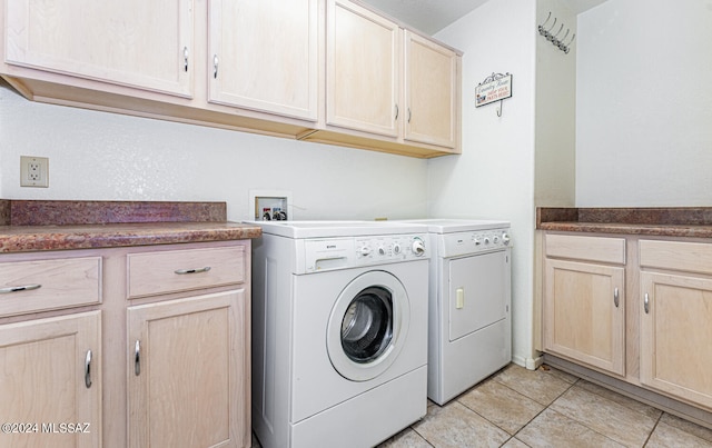 laundry room featuring washer and clothes dryer, cabinets, and light tile patterned floors