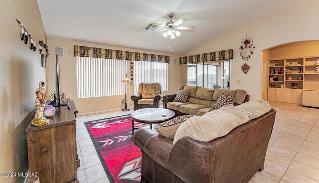 living room with built in shelves, light tile patterned floors, vaulted ceiling, and ceiling fan