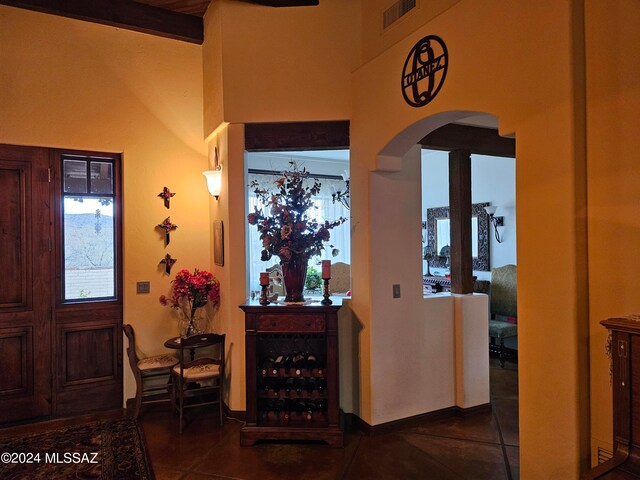 entrance foyer with high vaulted ceiling, dark tile floors, and beamed ceiling