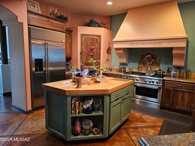 kitchen featuring green cabinetry, butcher block countertops, high end appliances, a center island, and custom range hood