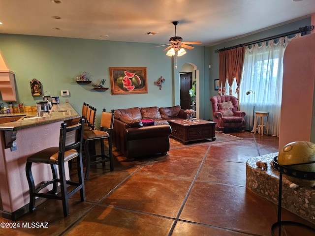 living room featuring ceiling fan and dark tile flooring