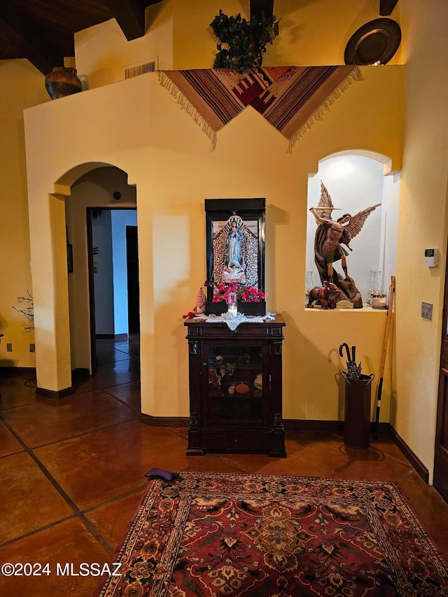 interior space with dark tile floors and beam ceiling