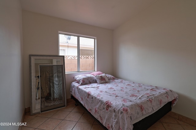 bedroom featuring lofted ceiling and light tile floors