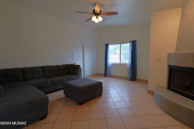 living room with ceiling fan, vaulted ceiling, a fireplace, and light tile floors