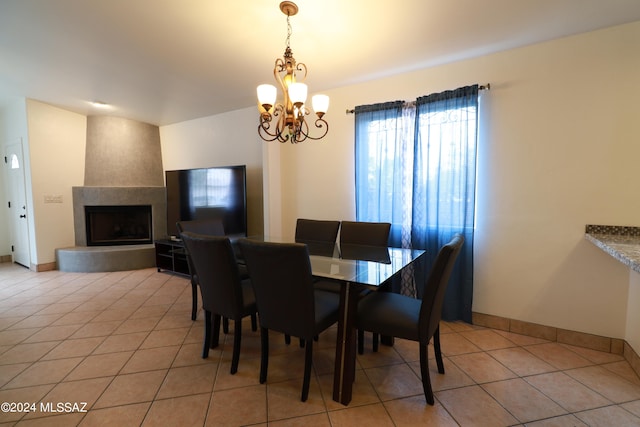 dining space featuring light tile floors, a chandelier, and a large fireplace