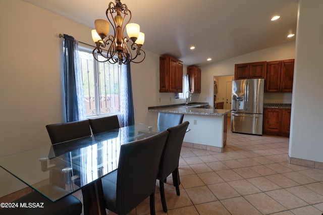 dining area with a notable chandelier, vaulted ceiling, sink, and light tile flooring