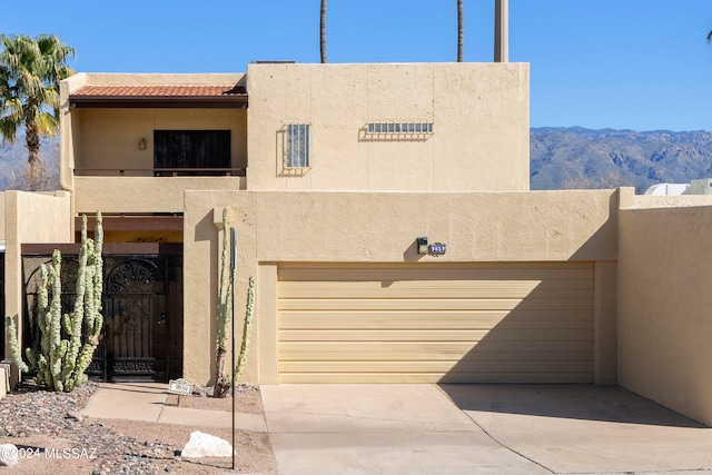 adobe home featuring a mountain view, a balcony, and a garage