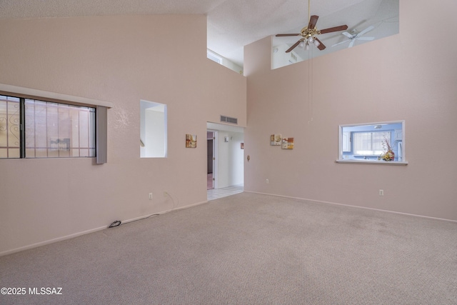 unfurnished living room featuring a high ceiling, ceiling fan, a textured ceiling, and light colored carpet