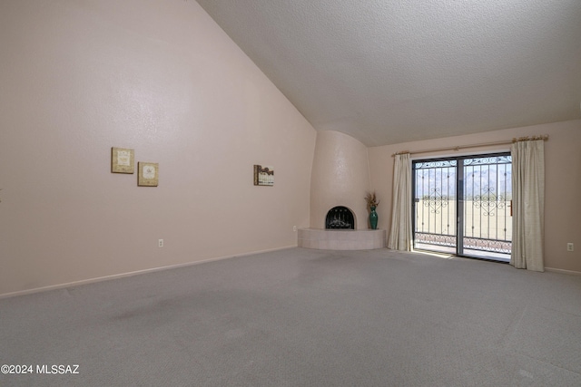 unfurnished living room featuring lofted ceiling, carpet floors, and a tiled fireplace