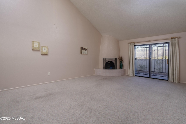 unfurnished living room with a textured ceiling, a tiled fireplace, vaulted ceiling, and carpet flooring