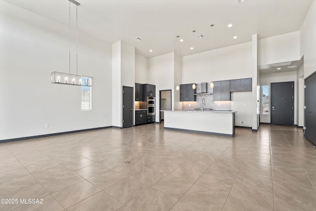 interior space featuring light tile patterned floors, baseboards, a towering ceiling, a chandelier, and a sink