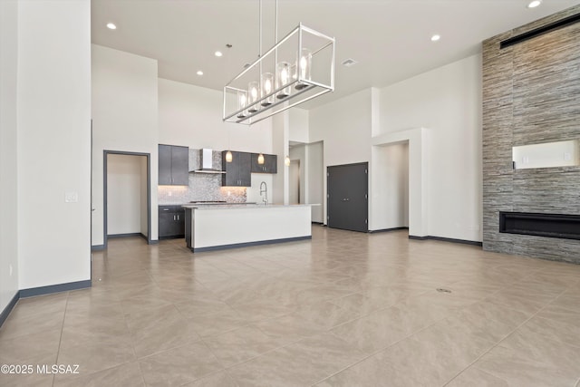 kitchen with wall chimney exhaust hood, a high ceiling, open floor plan, and light countertops