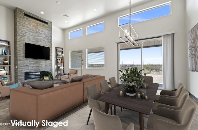 living area featuring plenty of natural light, light tile patterned flooring, a fireplace, and a towering ceiling