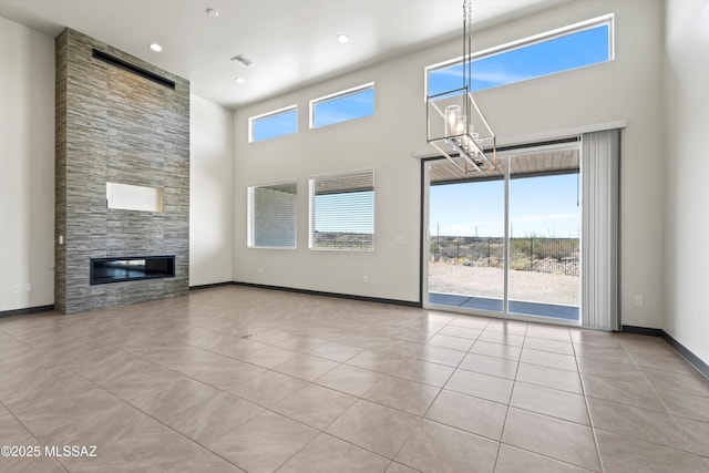 unfurnished living room with tile patterned flooring, recessed lighting, a towering ceiling, baseboards, and a tiled fireplace