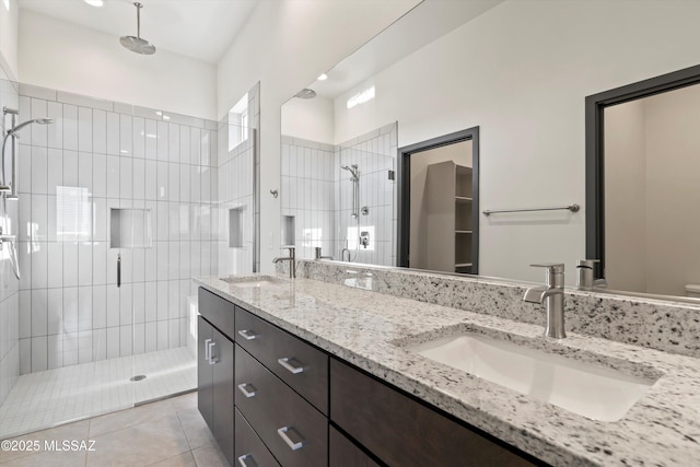 full bath with double vanity, tile patterned flooring, a shower stall, and a sink