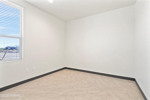 spare room featuring a healthy amount of sunlight and baseboards