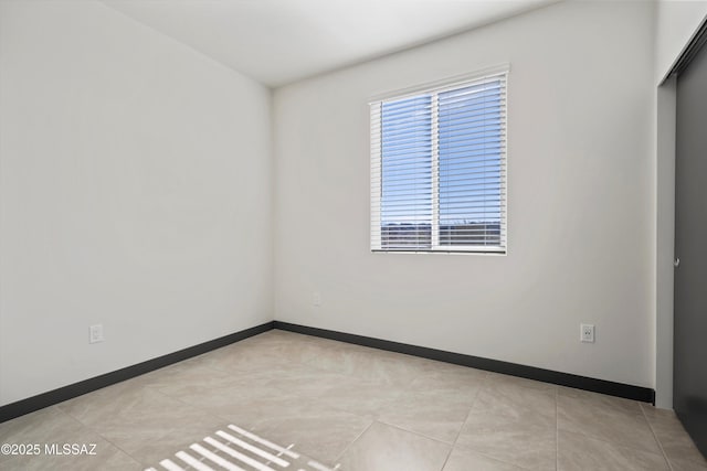 spare room featuring light tile patterned floors and baseboards