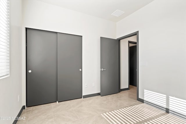 unfurnished bedroom featuring a closet, light tile patterned flooring, and baseboards