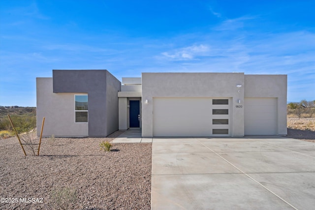 view of front facade with a garage, driveway, and stucco siding