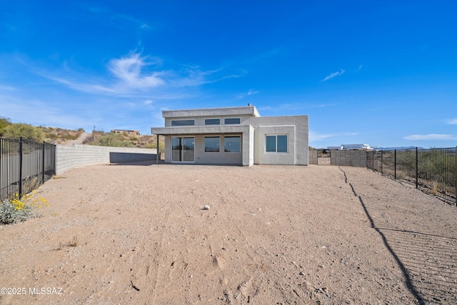 rear view of property featuring a fenced backyard and stucco siding