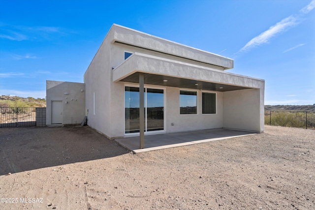 back of house with stucco siding, fence, and a patio