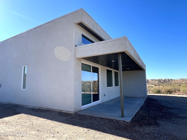 back of property featuring stucco siding, a patio, and fence