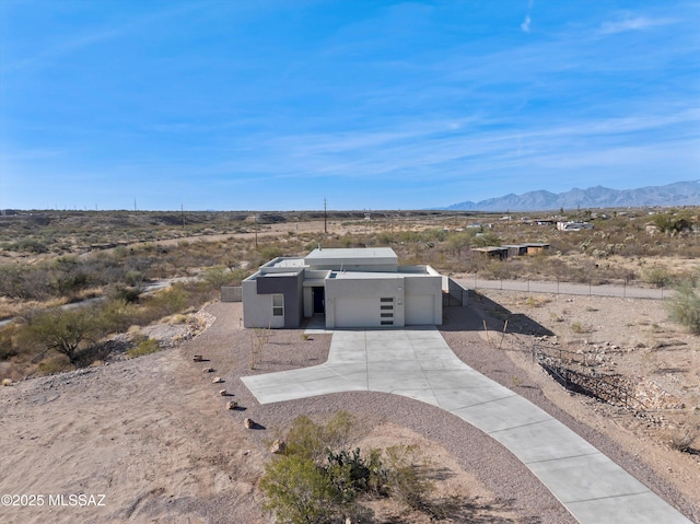 view of front of house with a garage, concrete driveway, a mountain view, and stucco siding