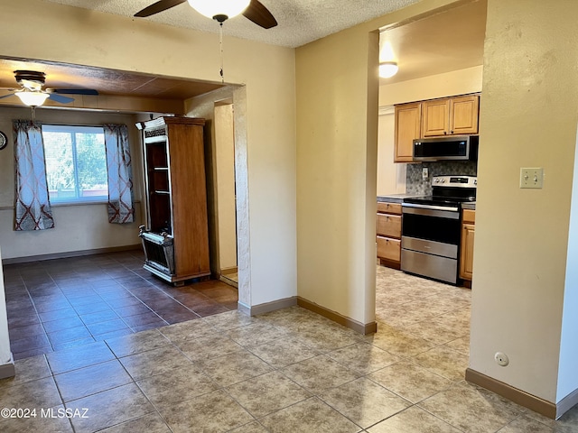 kitchen with light tile patterned flooring, a textured ceiling, ceiling fan, stainless steel appliances, and backsplash