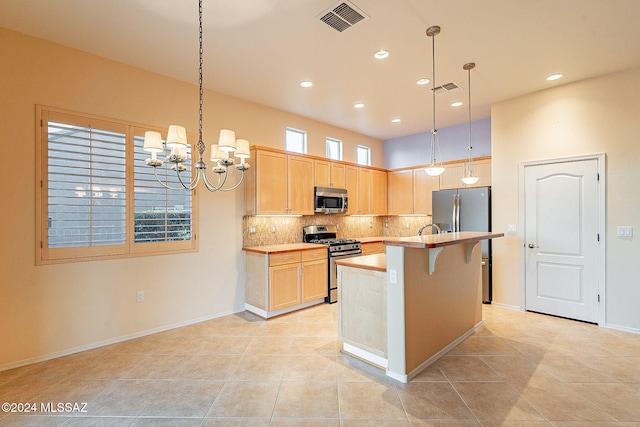 kitchen with decorative light fixtures, stainless steel appliances, light brown cabinetry, and a notable chandelier