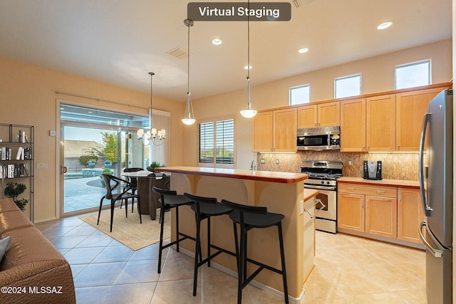 kitchen featuring a center island, a kitchen breakfast bar, hanging light fixtures, stainless steel appliances, and a chandelier