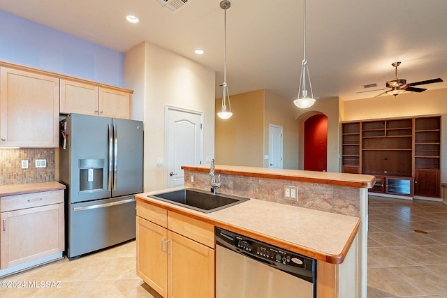 kitchen featuring decorative backsplash, light brown cabinetry, stainless steel appliances, a kitchen island with sink, and sink