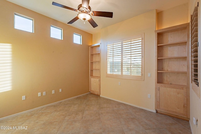 spare room featuring light tile patterned floors, ceiling fan, and built in shelves