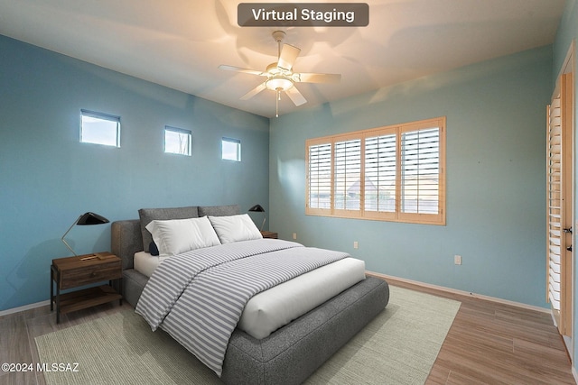 bedroom with wood-type flooring, multiple windows, and ceiling fan