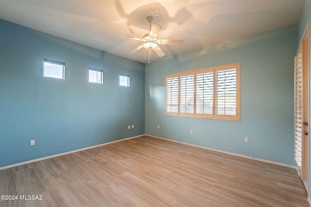 empty room featuring a wealth of natural light, ceiling fan, and light hardwood / wood-style floors