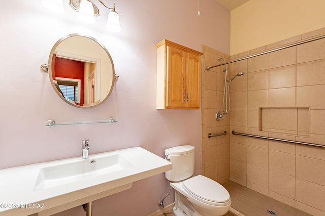 bathroom with tiled shower, sink, and toilet