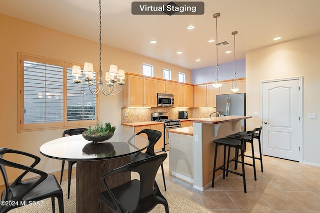 kitchen with appliances with stainless steel finishes, light brown cabinetry, pendant lighting, a chandelier, and a center island