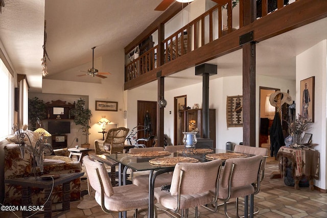 dining room featuring lofted ceiling, ceiling fan, and a wood stove