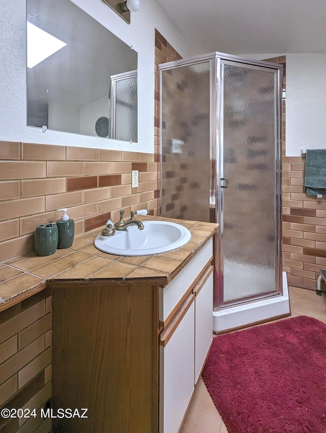 bathroom featuring tasteful backsplash, vanity, tile patterned flooring, and a shower with door