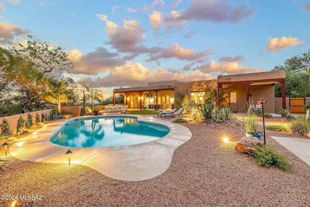 pool at dusk with a patio area