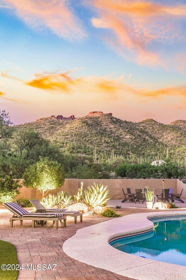 pool at dusk with a mountain view and a patio