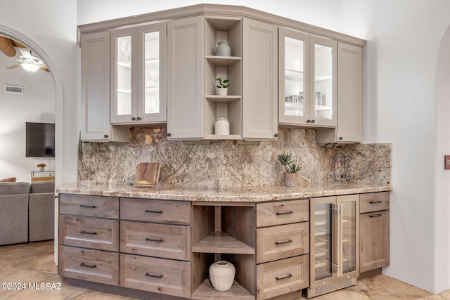 kitchen featuring light stone countertops, wine cooler, and tasteful backsplash